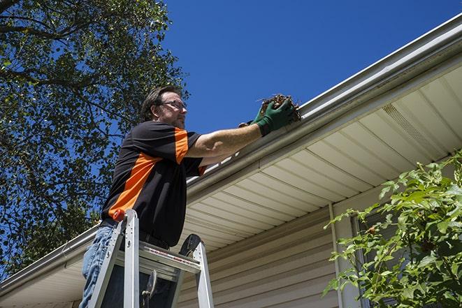 home improvement expert fixing gutters on a roof in Andover